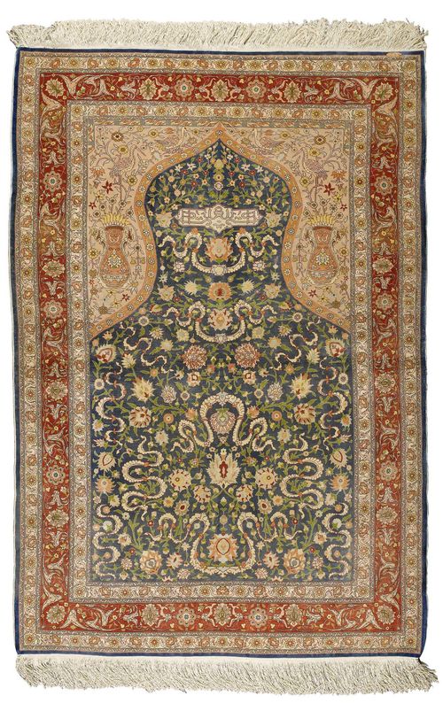 HEREKE SILK PRAYER.Blue mihrab with beige spandrels, finely patterned with trailing flowers and palmettes in harmonious colours, red border, 120x180 cm.