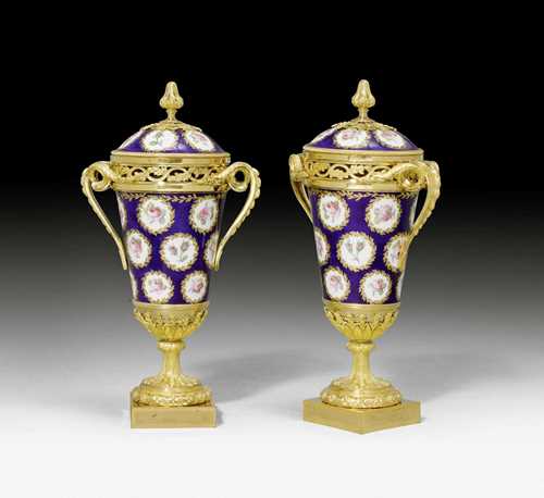 PAIR OF PORCELAIN VASES WITH BRONZE MOUNT, Louis XVI, porcelain from the Manufacture de Sèvres, bronze from Paris, end of the 18th century. Fine porcelain, painted with roses in white wreath rondelles on a cobalt blue ground and gilt bronze. Trophy-shaped vase. Minor losses and alterations. H 27 cm.