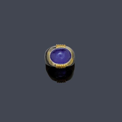 STAR SAPPHIRE AND DIAMOND RING, BINDER, ca. 1970. White and yellow gold 750, 30g. Casual, solid mantle ring, the top set with 1 fine, oval star sapphire of ca. 20.00 ct, closed setting, additionally decorated with 2 appliqued gold ornaments with 1 brilliant-cut diamond each, diamond weight ca. 0.06 ct. Size with adjustment insert ca. 50.