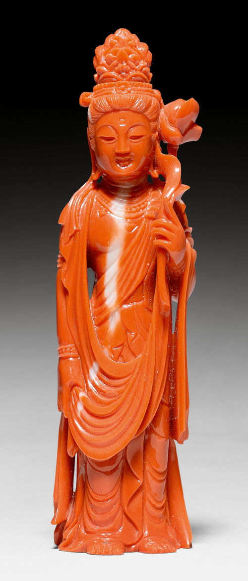 A RED CORAL FIGURE OF A STANDING BODHISATTVA WITH A LOTUS BLOSSOM.