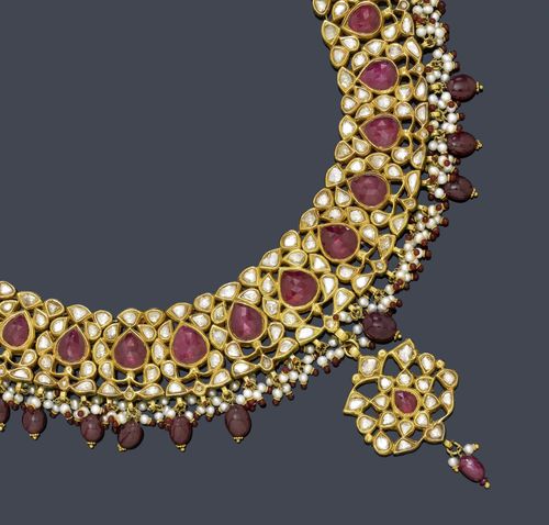 RUBY, DIAMOND, PEARL AND ENAMEL NECKLACE, India. Yellow gold. Decorative, elegant necklace, the middle part set throughout with numerous table-cut diamonds and 15 drop-cut rubies, graduated, and additionally decorated with 20 olive-shaped ruby pendants and numerous pearl pendants with a ruby as the lower part. In the centre, a florally open-worked pendant with numerous diamonds, 1 drop-cut ruby and 3 smaller pendants. The back finely enamelled in red-blue-green and white. On a corded band with adjustable length.