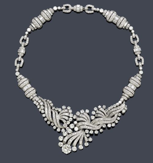DIAMOND NECKLACE, GÜBELIN, ca. 1950. Platinum 950, 116g. Very fancy necklace with diamond-set cylinder, stirrup and ring motifs, the asymmetrically designed front of curved, graduated, diamond-set band motifs, within a border of old European-cut diamonds. Suspended therefrom: 1old European-cut diamond weighing ca. 3.40 ct, ca. M-N/P1. Total weight of the 78 baguette-cut diamonds ca. 5.50 ct and total weight of the ca. 520 old European-cut and single-cut diamonds ca. 21.00 ct. L ca. 44 cm.
