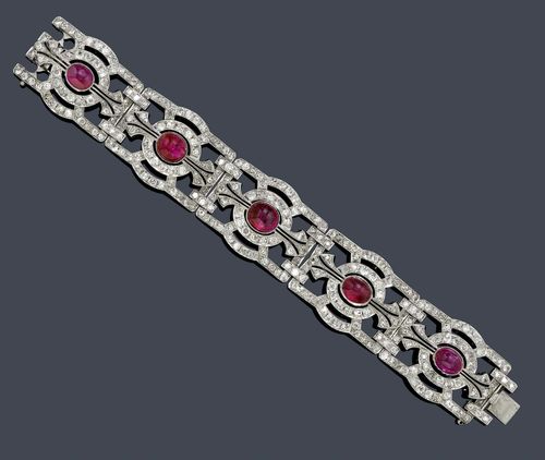 BURMA RUBY AND DIAMOND BRACELET, ca. 1935. White gold 750. Fancy bracelet of 5 geometrically designed, slightly convex links, each set with 1 Burma ruby cabochon weighing ca. 25.00 ct in total, untreated, and set throughout with 310 old European-cut diamonds weighing ca. 7.00 ct. W ca. 2.5 cm,  L ca. 16.5 cm. With GPL Report No. 06751, November 2012.