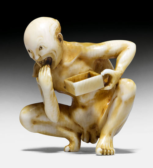 AN INVORY NETSUKE OF A NAKED MAN EATING IN A SQUATTING POSITION.