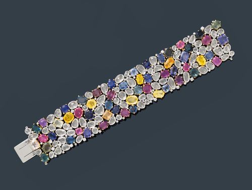 MULTI-SAPPHIRE AND DIAMOND BRACELET. White gold 750, 148g. Fancy, open-worked bracelet, set with 126 sapphires in different shapes and colours, weighing ca. 139.30 ct in total, in white gold collet settings. The intermediate spaces additionally decorated with 89 brilliant-cut diamonds, weighing ca. 2.10 ct in total, set in white gold chatons. W ca. 3.4 cm, L ca. 18 cm.