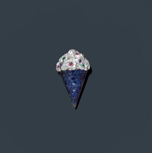 SAPPHIRE AND DIAMOND BROOCH. Yellow gold 750, rhodium-plated. Decorative original brooch designed as an ice cream cone. The ice cream is decorated with 1 brilliant-cut diamond of 0.07 ct, 3 rubies, 2 sapphires and 2 emerald cabochons. The cone is set throughout with numerous square-cut sapphires weighing ca. 9.20 ct in total, invisible setting. Ca. 4 x 2.5 cm.