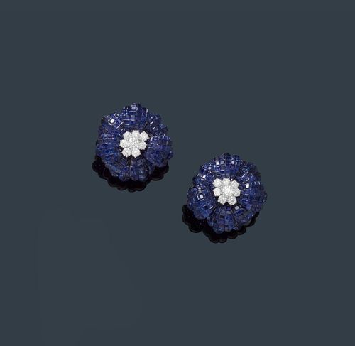 SAPPHIRE AND DIAMOND EAR CLIPS. White gold 750. Fancy, decorative ear clips with hinged studs designed as a stylized blossom. The petals set throughout with numerous, very fine, square-cut sapphires, weighing ca. 35.00 ct in total, invisible setting, the pistils set with a total of 16 brilliant-cut diamonds, weighing ca. 2.10 ct in total. Ca. 2.8 x 2.7 cm.