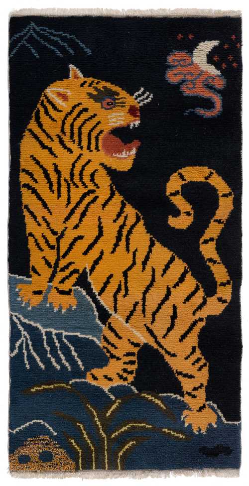 A POLYCHROME WOOL CARPET WITH A ROARING TIGER ON A ROCK.