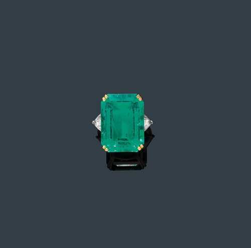 EMERALD AND DIAMOND RING, ca. 1990. Yellow gold 750 and platinum. Classic-elegant ring, the top set with 1 fine, step-cut Columbian emerald weighing 28.21 ct, flanked by 2 trilliant-cut diamonds weighing ca. 2.20 ct. Size ca. 53. With G&#252;belin Report No. 9711125, December 1997.