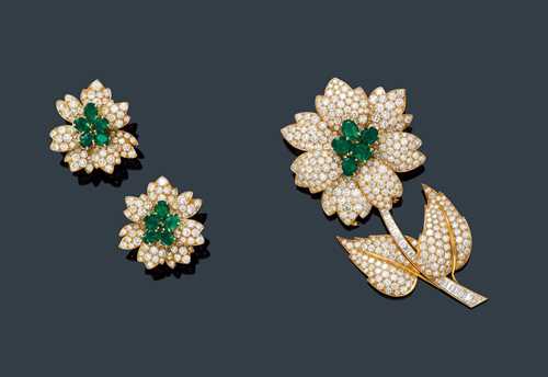 EMERALD AND DIAMOND CLIP BROOCH WITH EAR CLIPS, VAN CLEEF & ARPELS, ca. 1980. Yellow gold 750. Elegant, large brooch designed as a flower, the blossom set with 5 oval, probably Zambian emeralds weighing ca. 5.00 ct, set throughout with ca.  216 brilliant-cut diamonds weighing ca. 8.50 ct, 1 missing. The removable stem has 2 leaves, set throughout with numerous baguette-cut diamonds weighing ca. 1.70 ct, and brilliant-cut diamonds weighing 4.30 ct. L ca. 9 cm. Matching blossom-shaped ear clips with studs, each set with 5 emeralds, weighing ca. 3.00 ct in total, set throughout with numerous brilliant-cut diamonds weighing ca. 4.30 ct. Ca. 3 x 3.2 cm. With original case.