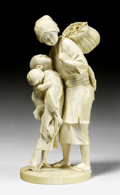 AN IVORY OKIMONO OF A LADY WITH FRUIT BASKET HUGGING A GIRL WITH LITTLE BOY. Japan, Meiji period, height 24.5 cm. Signed: "Maruki sei". Very minor damage.