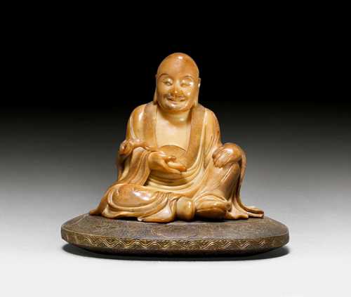 A SOAPSTONE CARVING OF A SEATED LUOHAN ON A OVAL BASE. China, 17th c. Height 9.6 cm. Signature: Wei Rufen zhi. Very minor chips.