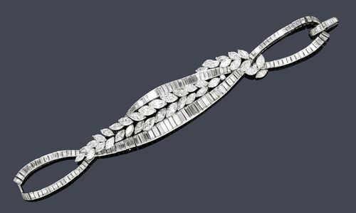 DIAMOND BRACELET, KUTCHINSKY, ca. 1950. Platinum 850, 75g. Very fancy bracelet of 2 long, intersecting, stylized band motifs set throughout with ca. 155 baguette-cut diamonds weighing ca. 19.00 ct, the central part additionally decorated with stylized leaf motifs set with 39 navette-cut diamonds weighing ca. 12.00 ct and 1 brilliant-cut diamond, signed Kutchinsky, Platinum. L 18 cm. With original case.
