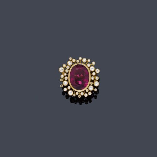 SPINEL AND DIAMOND RING. Yellow gold 750, 20g. Decorative ring, the top set with 1 fine, red-violet, oval spinel of ca. 7.00 ct within a border of ca. 40 brilliant-cut diamonds of different sizes set in cylindrical settings, total weight of the diamonds ca, 0.60 ct. Size ca. 55. Tested by Gemlab.