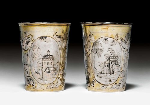 PAIR OF BEAKERS,Leipzig ca. 1700. Maker's mark Johannes Paul Schmidt. Parcel-gilt. Conical form with stepped lip edge. Wall with chased, embossed and chiselled architectural depictions in medallions. Retracted bottom with embossed and engraved number. H ca. 10 cm, total weight 205g. Provenance: German private collection.