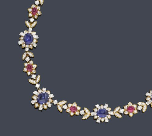 RUBY, SAPPHIRE AND DIAMOND NECKLACE. Yellow gold ca. 730 and white gold ca. 670. Attractive, elegant necklace of 8 stylized flower motifs, each set with 1 sapphire cabochon within a border of diamonds, alternately mounted between 8 small flower motifs, each of which is set with 1 ruby cabochon within a border of 6 brilliant-cut diamonds and numerous leaf motifs. Total weight of the sapphires ca. 34.70 ct, of the rubies ca. 11.80 ct and of the brilliant-cut diamonds ca. 18.40 ct. L ca. 41 cm.