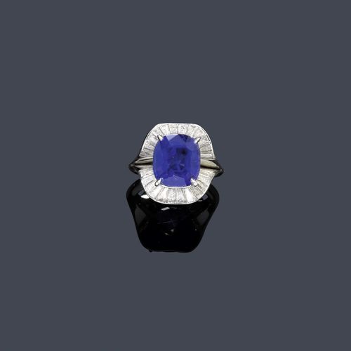 BURMA SAPPHIRE AND DIAMOND RING, E. MEISTER, 1972. White gold 750. Classic-elegant ring, the top set with 1 very fine, antique-oval Burma sapphire of 8.03 ct, unheated, within a border of 24 trapeze-cut diamonds weighing ca. 1.20 ct. Shank with a dated engraving. Size ca. 52. With Gübelin Report No. 0706216, June 2007.