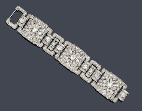 DIAMOND BRACELET, ca. 1930. Platinum. Fancy Art Deco bracelet of 3 geometrically open-worked links in the shape of a square with rounded edges and 3 rectangular intermediate links set with 8 old European cut diamonds weighing ca. 5.50 ct and set throughout with ca. 760 old European cut and single-cut diamonds weighing ca. 20.00 ct. W ca. 3 cm, L ca. 17.8 cm.