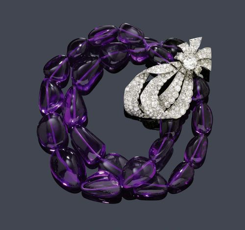 AMETHYST AND DIAMOND BRACELET, CARTIER, ca. 1960. Platinum. Decorative, double-row bracelet of 25 baroque amethysts, graduated from ca. 14 x 10 to 22 x 17 mm. Fancy clasp designed as a bow, set with 1 old-European cut diamond weighing ca. 1.00 ct, and set throughout with numerous old-European cut and single-cut diamonds weighing ca. 6.00 ct in total. Signed Monture Cartier, 9.30.60 monogram S.P.L. maker's mark, clasp in white gold. L ca. 22 cm.