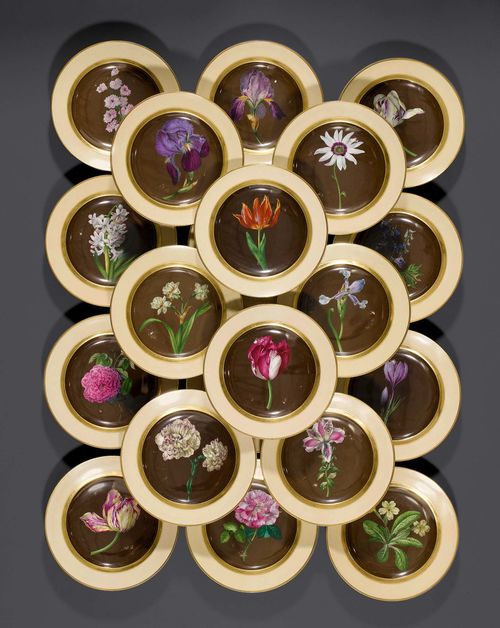 23 'CONFECT TELLER MIT ALLERLEY BLUMEN' PLATES, VIENNA, circa 1819. Each plate painted with a plant on black-brown ground. Verso inscribed in black with the respective botanical names. Underglaze blue beehive mark, impressed mark and year stamp, D 24.4 cm. 1 plate with a chip to the edge, 1 with 2 chips to the edge, 1 fully repaired, minor rubbing of colors. (23)