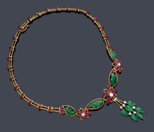 RUBY, EMERALD AND DIAMOND NECKLACE, GÜBELIN, ca. 1950. Yellow gold 750. Decorative "Y"-shaped necklace of corded gold wires and ruby-set barrette intermediate links. Towards the front: additionally decorated with engraved, leaf-shaped emeralds and 3 blossom motifs with rubies and brilliant-cut diamonds. The lower part: 1 pendant with 6 engraved emeralds and 9 brilliant-cut diamonds. Total weight of the rubies and of the diamonds ca. 0.90 ct. Maker's mark Gübelin, No. 204419. L ca. 38.5 cm. With original case.