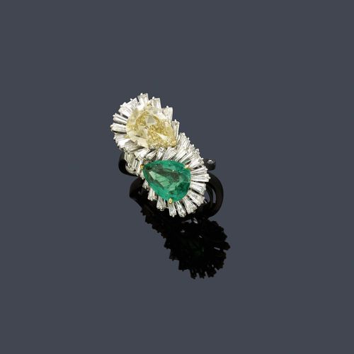 DIAMOND AND EMERALD RING, ca. 1950. White and yellow gold 750 and platinum. Elegant cross-over model, the top set with 1 naturally coloured, fancy light yellowish-brown drop-cut diamond of 3.20 ct, ca. VS1, Type IIA, and 1 Columbian drop-cut emerald, insignificantly oiled, of ca. 2.50 ct, within a border of 36 trapeze-cut diamonds weighing ca. 2.00 ct. Size ca. 55, with size adjustment insert. With case. Tested by Gemlab.