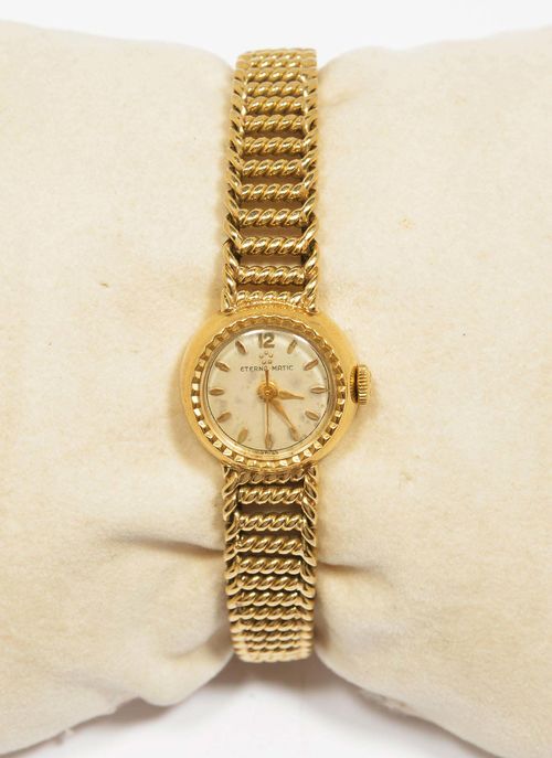 LADY'S WRISTWATCH, ETERNA-MATIC, ca. 1960. Yellow gold 585, 33g. Small, round case No. 4046413 with corded lunette. Silver-coloured dial with gold-coloured indices and hands, oxidized. Automatic, movement No. 3971238, Cal. 14014. Geometrically open-worked, textured gold band, not original. L ca. 17.5 cm.