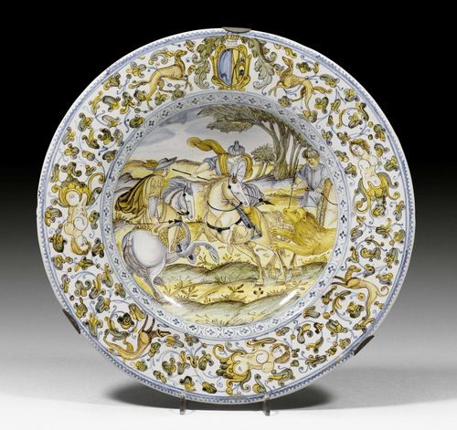 MAIOLICA PLATTER 'CACCIA AL LEONE',Castelli d'Abruzzo, workshop of Francesco Grue, circa 1660-70. Painted with a lion hunt in the tradition of Antonio Tempesta (1555 Florence 1630), dominated by a European and two Oriental hunters on horseback, the rim with coat of arms, probably of the 'Marchesi di Quinzi di l'Aquila'. D 29 cm. Provenance: - Oscar Bondy collection, Vienna. - Restituted in 1948 to the collector's heirs. - Blumka Collection, New York - Sotheby's New York, European Works of Art from the Private Collection and Gallery of the Blumka Estate, 9th-10th January 1996, Lot 37. - Kunsthandel Segal, Basel. - Private collection, Geneva.