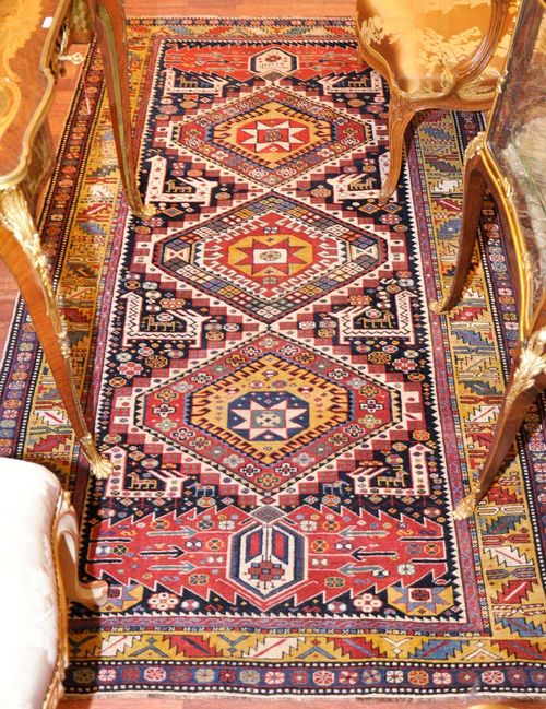 KARAGHASHLI antique, dated 1901.Dark central field with three bulky medallions. The entire carpet is geometrically patterned with stylised plants and animals. Yellow wine glass border. Good condition. 114x200 cm.