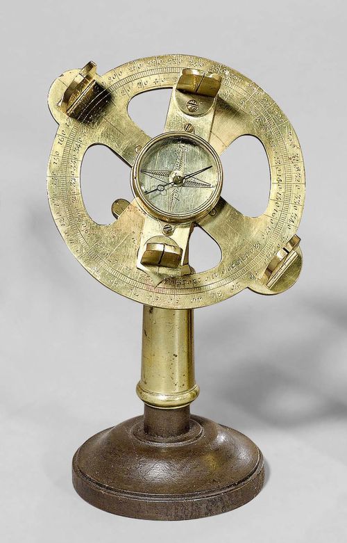A HOLLAND CIRCLE, France, 18th c. Engraved brass. The base with central compass, wind rose and directions, 2 sights. Rotating alidade with another 2 sights. Ball-and-socket joint on wooden plinth. D ca. 11 cm.
