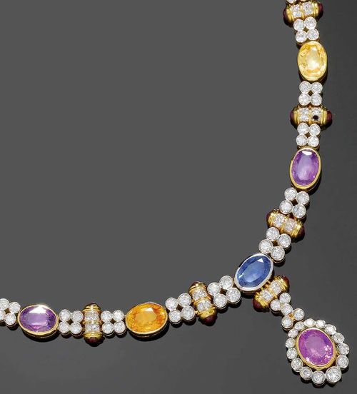 MULTICOLOR SAPPHIRE AND BRILLIANT-CUT DIAMOND NECKLACE. Yellow gold 750. Very stylish "Y"-necklace set with 16 graduated oval sapphires of different colours, alternately set in between four brilliant-cut diamond pairs and one brilliant-cut diamond-set cylinder motif with 1 ruby cabochon on each end. The pendant is set with 1 oval purple sapphire in a brilliant-cut diamond surround mounted under two brilliant-cut diamond pairs and one cylinder motif. Total weight of the sapphires ca. 40.77 ct, of the ruby cabochons ca. 8.35 ct and of the 215 brilliant-cut diamonds ca. 7.32 ct. L 42.5 cm.