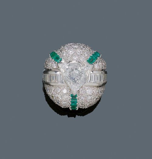 DIAMOND AND EMERALD RING, ca. 1960. Platinum. Fancy ring, the convex top set with a trilliant-cut diamond of ca. 3.80 ct ca. N/ST1, flanked by 22 baguette-cut diamonds weighing ca. 1.50 ct and set throughout with ca. 90 brilliant-cut diamonds weighing ca. 2.00 ct, additionally decorated with 3 square-cut emerald lines weighing ca. 0.50 ct. Size ca. 59. Tested by Gemlab. From the heirs of Baron Anton Kiss (1880-1970), son of Katharina Schratt, Schloss Mondsee.