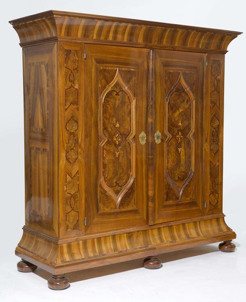 CUPBOARD,Baroque, Switzerland or Southern Germany, 18th century. Walnut, burlwood and plum inlaid with geometric reserves, bands and leaves. Rectangular body.  Chased brass mounts. 204x73x210 cm. 1 key. Restored, in good condition.