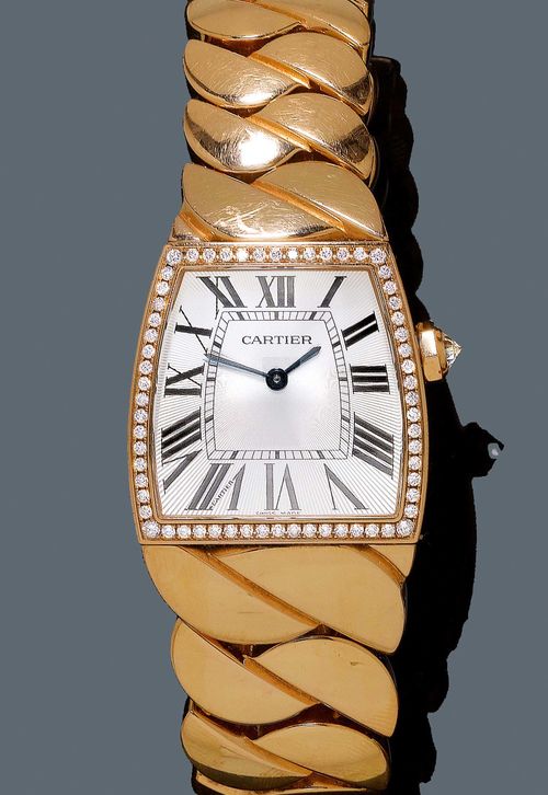 DIAMOND LADY'S WRISTWATCH, CARTIER LA DONA. Red gold 750. Ref. WE601008. Asymmetrical, trapezoidal case No. 2896 119683LX with brilliant-cut diamond lunette. Silver-coloured dial with Roman numerals and blue-Breguet hands. Quartz movement, Cal 690. Solid gold band with fold-over clasp. From the estate of Charlotte and Egon Karter-Sender, Basel.