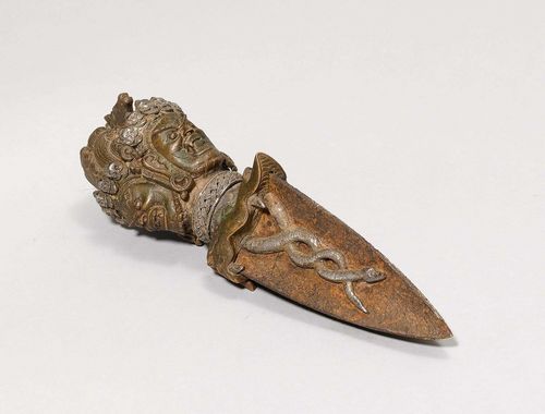 PHURBU.Tibet, L 24 cm. Copper, iron and silver. The handle with three wrathful faces, crowned by a horse's head. A silver band on the neck. The three-sided iron blade is ornamented with silver snakes.
