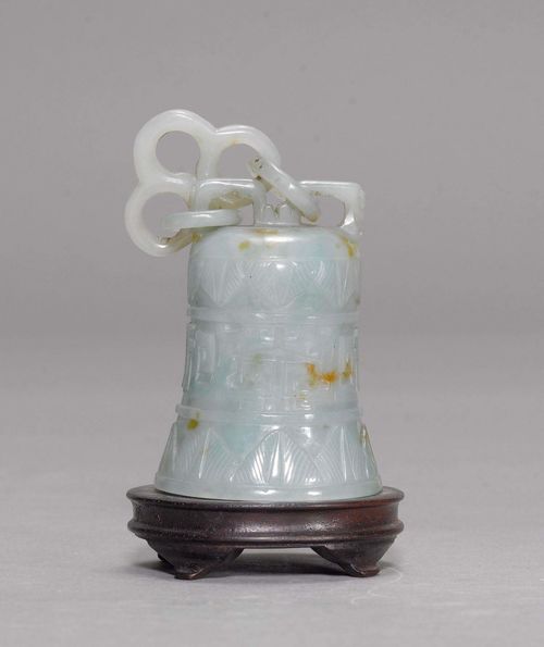 JADEITE BELL.China, 19th/20th c. H 9.5 cm. Greenish jadeite with brown inclusions. The bell has openwork rings attached. Body shows a bas-relief decoration of leaves and dragons in three registers. Wooden pedestal.