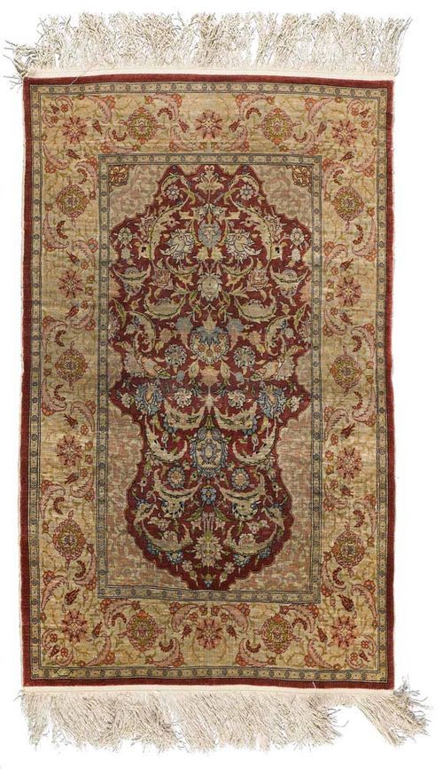 HEREKE silk, old.Red mihrab with light corner motifs, the entire carpet is patterned with trailing flowers and palmettes in delicate pastel colours, beige border, slight wear, 125x75 cm.