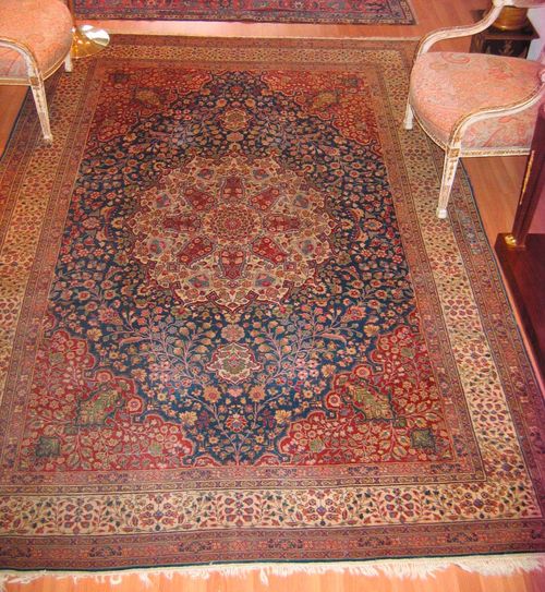 TABRIZ old.White central medallion on a blue ground with red corner motifs, the entire carpet is finely patterned with trailing flowers in harmonious colours, white border, slight wear, 308x210 cm.