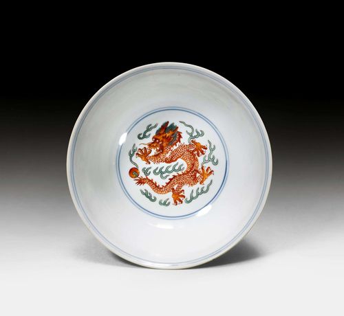 WUCAI DRAGON AND PHOENIX BOWL.China, Qianlong mark and of the period, D 15 cm. Exterior shows red and green dragons, both five-clawed, on a ground of flowers and scrolls. Between them are two phoenixes. In the well a dragon is depicted frontally among clouds. Underglaze blue Qianlong seal mark in the foot. Break with glue repair and two short hairline cracks.
