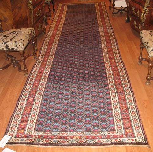 CAUCASIAN RUG old.Dark central field with small stylised flowers in blue and violet. Red and white border. Good condition, 470x120 cm.