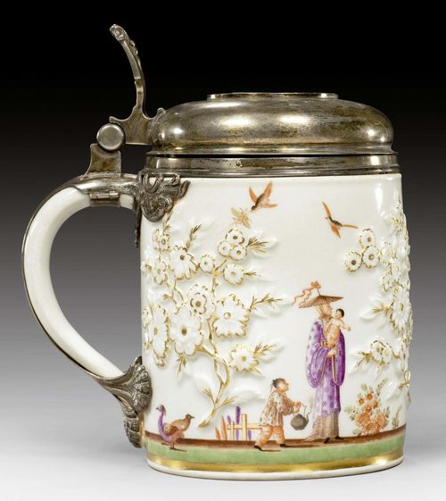 TANKARD WITH CHINOISERIE DECORATION, MEISSEN, CIRCA 1730-35. With silver mount, Dresden, circa 1750. With applied oriental style floral sprays in gold and painted in the style of J.G. Hoeroldt with continuous chinoiserie scene, together with birds and Indianische Blumen. Mounted with silver lid decorated in rocaille and with palmette thumb rest. A coin in the lid dated 1722, with the portrait of Friedrich August I, Elector of Saxony and Poland 'D.G.FRID.AUGUST REX POL DUX SAX I C.M.A. & W', verso crowned coat of arms of Saxony and Poland, with text 'SAC ROM IMP ARCHIM ET ELECTOR'. Underglaze blue sword mark. Mounts partly from the 19th century. H 13cm. Restored. Provenance: - Private collection, Germany. - Galerie Koller, Auction 21.3.2002. - Private collection, Switzerland . Marc Rosenberg, Der Goldschmiede Merkzeichen, 3rd edition, Frankfurt 1923, vol. 2.