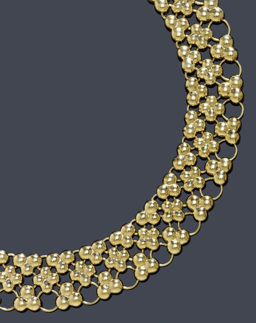 A GOLD NECKLACE WITH A BRACELET. Yellow gold 750, 229g. A stylish broad necklace composed of multiple reticulate trifoil and quadrifoil stylized clusters. L ca. 42 cm, Width ca. 2,3 cm. Matching bracelet. L ca. 17,5 cm, Width 3 cm. With a case by Adler, Geneva