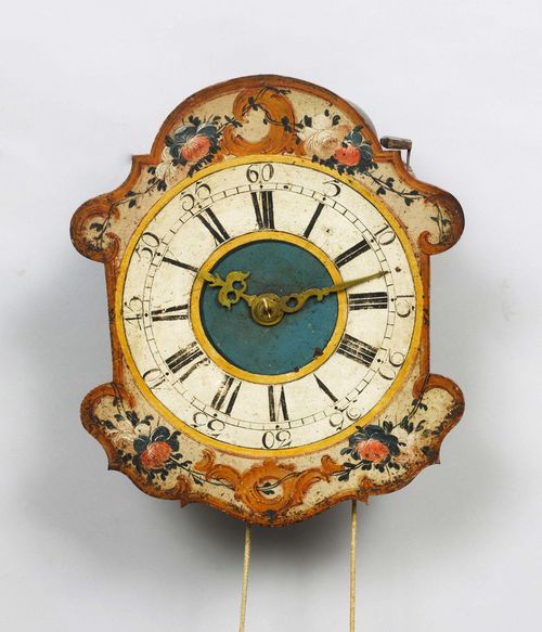 WALL CLOCK,Eastern Switzerland, 18th century. Metal dial, painted with flowers and rocailles. Turned wood movement with brass cog wheels. Anchor escapement striking the hour on bell. H 33 cm.