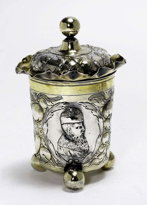 BEAKER WITH COVER,in the style of the 17th century. Partially gilt. Chased and embossed walls, men in profile between bunches of fruit on all sides. On 3 spherical feet. H 18 cm, 339 g.