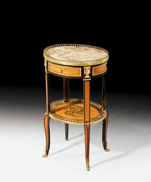 OVAL GUÉRIDON,Transition, stamped C. TOPINO (Charles Topino, maitre 1773), Paris circa 1775. Tulipwood and various precious woods in veneer and inlaid with rosette, laurel wreath and frieze. The pink/grey speckled marble top within a pierced bronze rail. One drawer at the front. Matte and polished gilt bronze mounts and sabots. 42x35x72 cm. Provenance: from an important European collection. A fine guéridon in good condition.