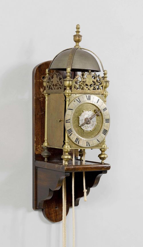 LANTERN CLOCK WITH ALARM,England, 17th century. Bronze and brass. Rectangular case with spherical feet, and bell on top. Front engraved with leaf tendrils. Silver-plated chapter ring and engraved alarm disc. Movement striking the 1/2-hour on bell. Alarm on bell. 18x17x49 cm. Movement, altered.