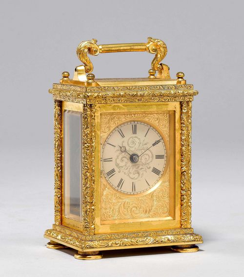 TRAVEL CLOCK,England, middle of the 19th century. Brass, engraved with tendrils and frieze, and gilt. Rectangular case with handle, glazed on three sides. Engraved brass front with beige enamel dial. Movement with main spring. 8.5x6.5x12 cm. In leather-lined case. 1 key.
