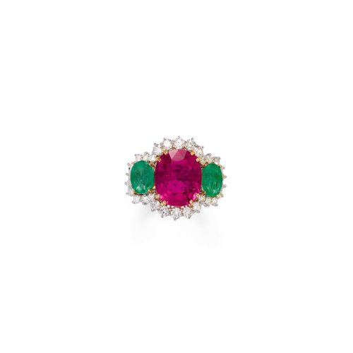TOURMALINE AND EMERALD RING. White gold 750. Attractive ring, the top set with 1 antique-oval, purple tourmaline weighing ca. 11.00 ct, flanked by 2 oval emeralds weighing ca. 4.00 ct and within a border of 30 brilliant-cut diamonds weighing ca. 2.50 ct. Size ca. 55.