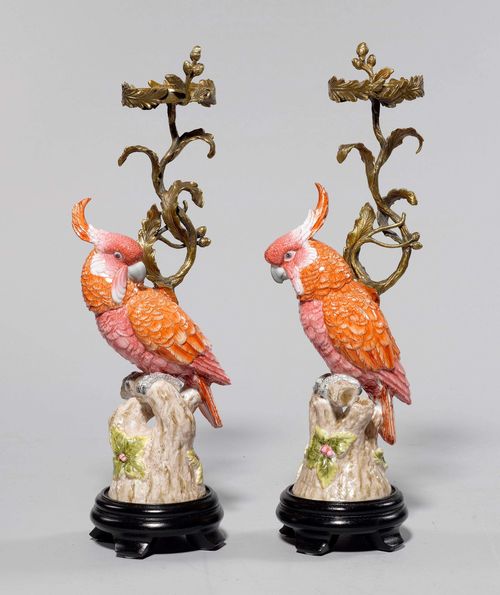 PAIR OF CANDLEHOLDERS WITH PARROTS, in the style of the 18th century. Porcelain. Parrot sitting on a branch, with a curved bronze light branch and a round drip pan. On a round wooden plinth. H 44 cm.