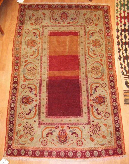 ANATOLIAN antique.Narrow central field in red and beige, wide border with trailing flowers, signs of wear, 145x100 cm.